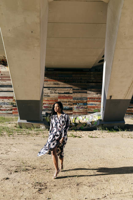 Женщина в красивом платье позирует под городским мостом — стоковое фото