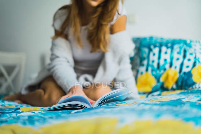 Frau liest Buch auf dem Bett — Stockfoto