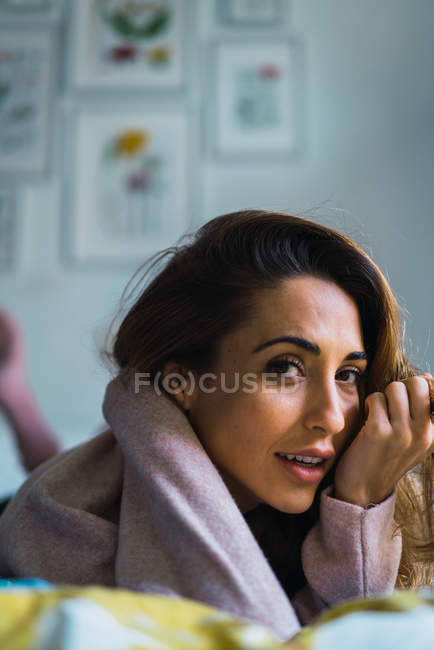 Retrato de mulher olhando para a câmera enquanto deitada na cama . — Fotografia de Stock