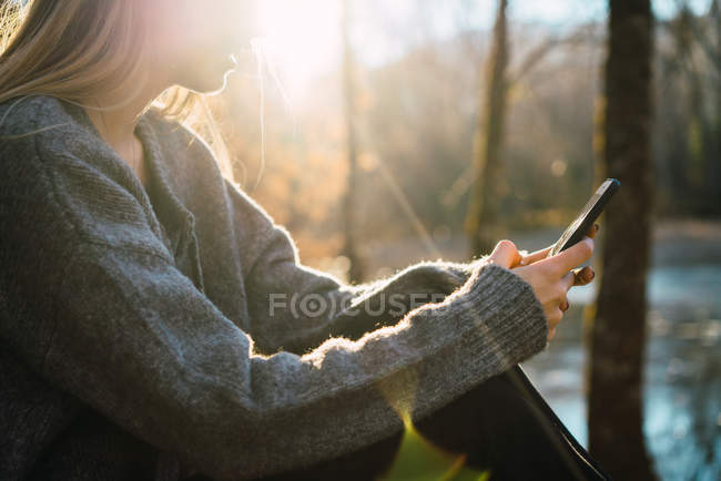 Обтинання жінка перегляду смартфон в осінній ліс — стокове фото