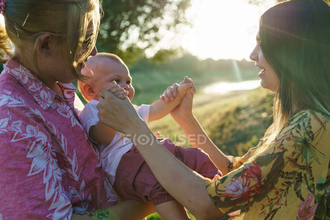 Side view of happy lesbian couple cuddling with child — Stock Photo