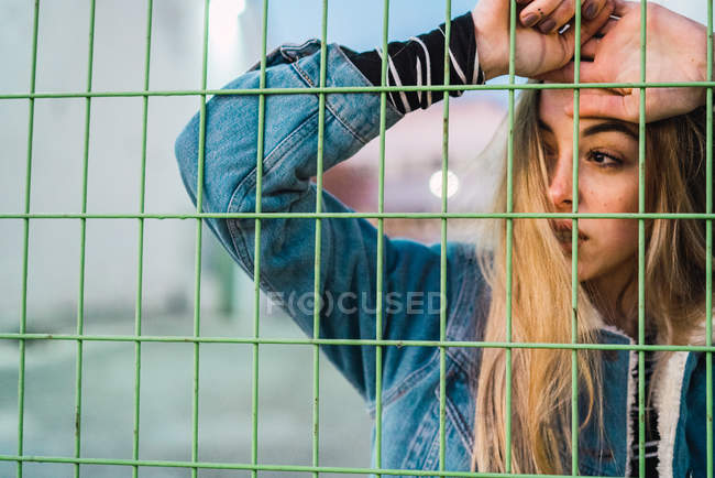 Portrait de femme blonde sensuelle posant derrière une clôture métallique — Photo de stock