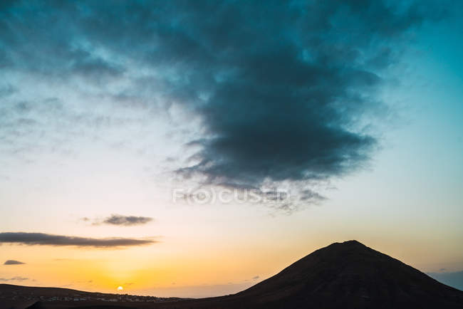 Paesaggio del cielo al tramonto con lievi nuvole sopra la silhouette nera della montagna . — Foto stock