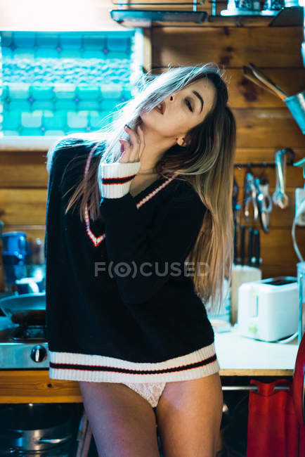 Provokantes Mädchen im Pullover posiert auf Küchentisch — Stockfoto