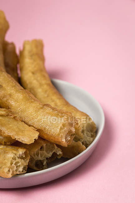 Typical Spanish churros in plate on pink — Stock Photo