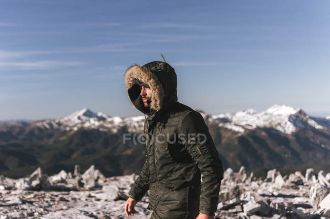 Vue latérale de l'homme en vêtements de dessus marchant sur des montagnes enneigées paysage — Photo de stock