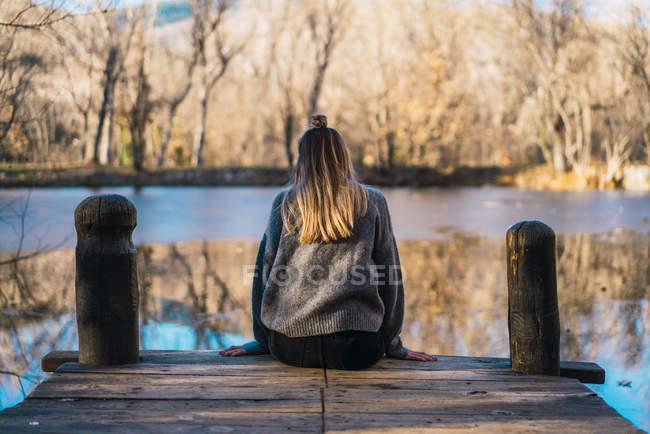 Rear view of woman on autumnal pier above pond — Stock Photo