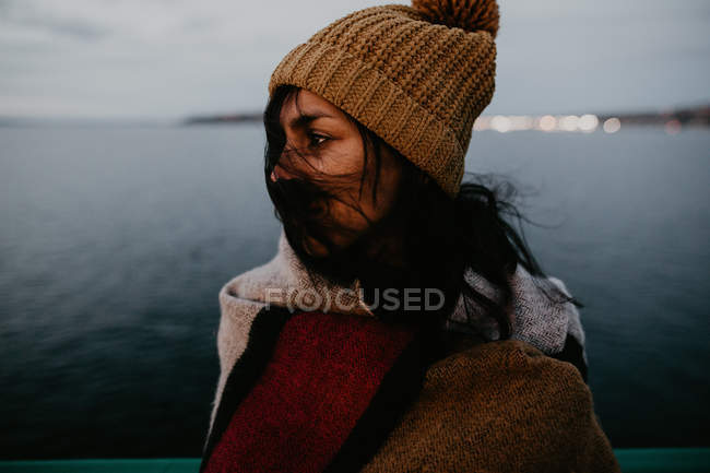 Side view of young woman posing in wind on background of seascape — Stock Photo