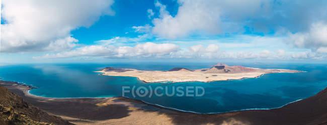 Vista panorámica lejana de la pequeña isla en el mar azul - foto de stock