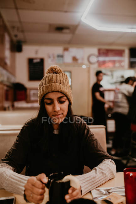 Retrato de una joven sentada en la mesa del café y tomando café . - foto de stock