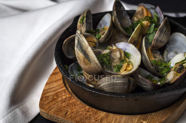 Close up view of clam stew with white wine sauce served in rural pan on wooden board — Stock Photo
