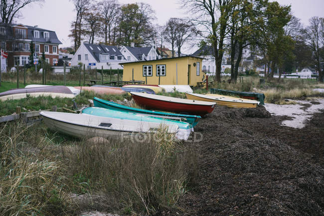 Рядок невеликі човни, які розміщені на березі в невеликих будинків у сільській місцевості. — стокове фото