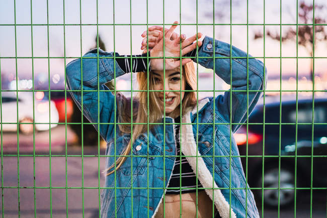 Seductive young blonde posing behind net fence — Stock Photo