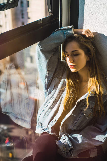 Stilvolles Mädchen posiert in der Nähe von Fenster im Sonnenlicht — Stockfoto