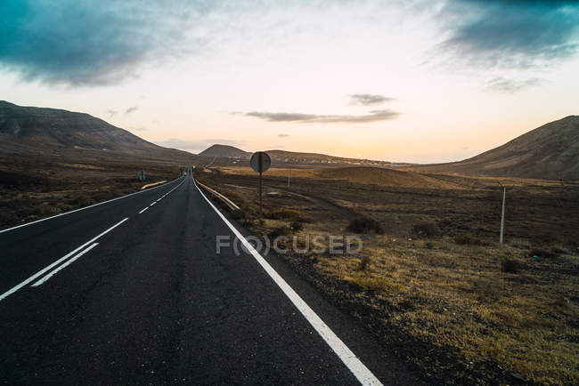 Paisagem de estrada bonita atravessando terreno infinito espaçoso com colinas . — Fotografia de Stock
