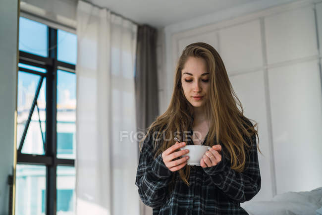 Портрет молодой женщины с чашкой кофе дома — стоковое фото
