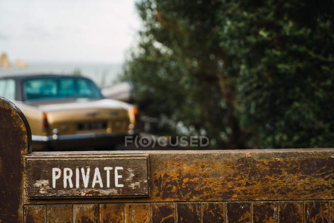 Private sign on wooden fence and golden vintage car at bush. — Stock Photo
