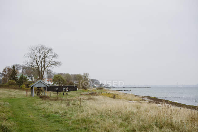 Paesaggio di terre costiere e pozzo con serratura in legno — Foto stock