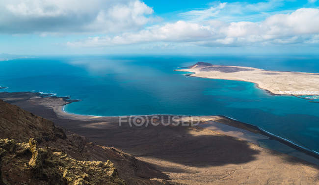 Vista panorámica de la costa y la pequeña isla en el océano azul - foto de stock