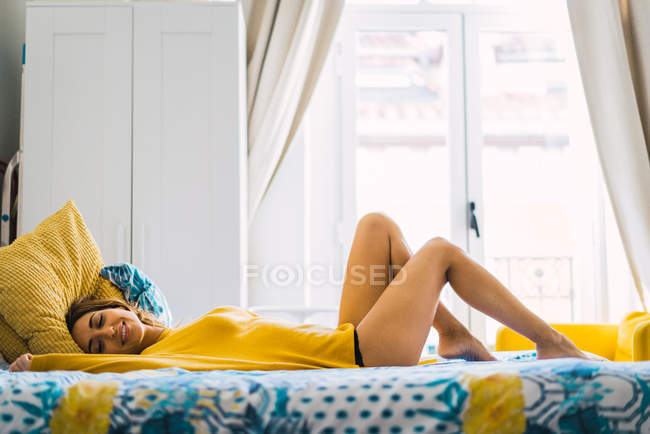 Vista lateral da mulher sorridente deitada na cama — Fotografia de Stock