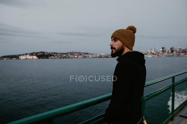 Vista lateral del hombre barbudo de pie en ferry flotando en el océano . - foto de stock