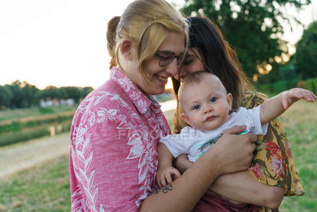 Мила дитина на руках лесбійської пари — стокове фото