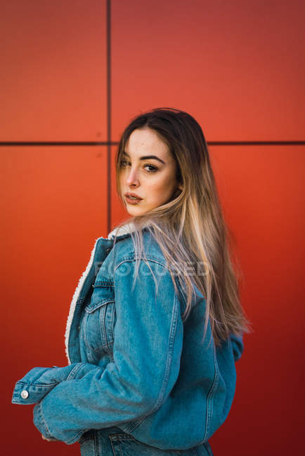 Стильна молода жінка зачаровує на фоні помаранчевої стіни — стокове фото