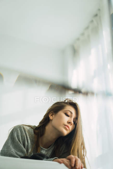 Vista de ángulo alto de la mujer en suéter abrazándose en la cama y mirando hacia abajo - foto de stock