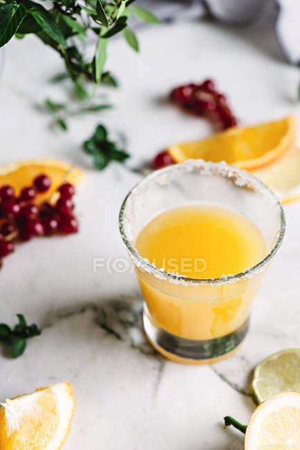 Low angle view of glass with orange juice with berries on white table — Stock Photo