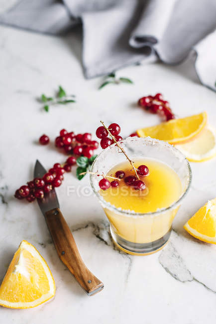 Still life of glass with orange juice with berries on white table — Stock Photo