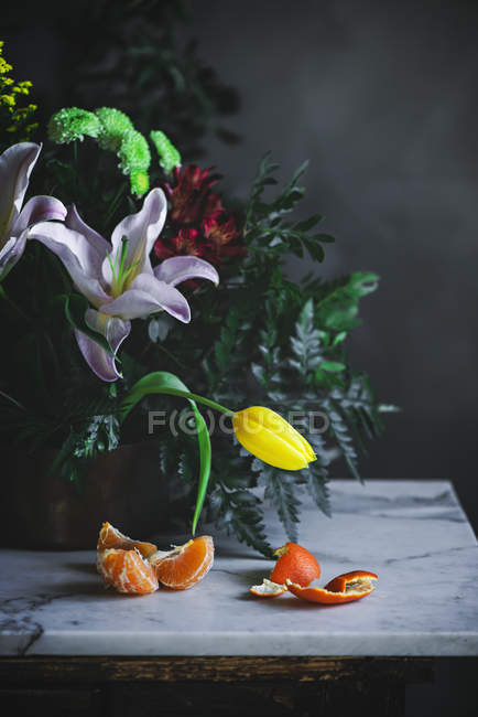 Natureza morta de flores Buquê na mesa com pedaços de tangerina — Fotografia de Stock