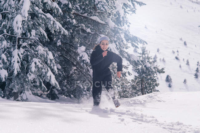 Front view of sportive woman running rapidly at snowy countryside — Stock Photo