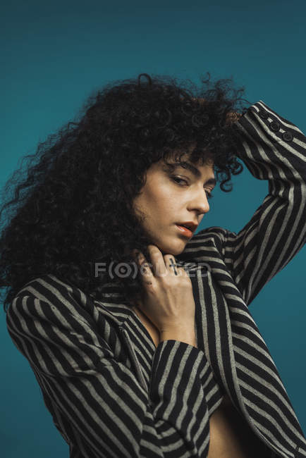 Curly woman in striped jacket posing in studio — Stock Photo