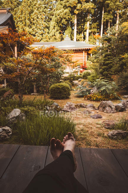 Cultiver les jambes de la personne assise et reposant dans le jardin asiatique traditionnel . — Photo de stock