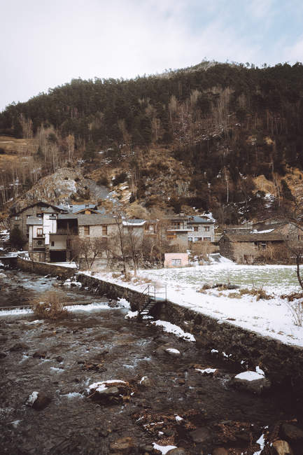 Vista a las casas rurales del pueblo en el césped nevado en las montañas . - foto de stock