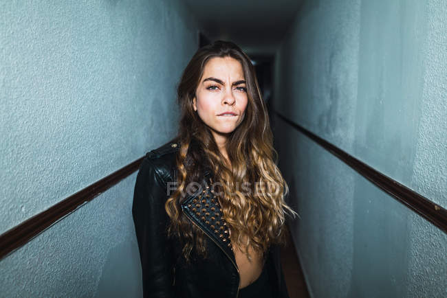 Suspicious woman posing in corridor and looking at camera — Stock Photo