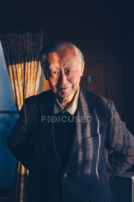 Retrato de hombre asiático adulto mayor en traje de pie en casa. - foto de stock