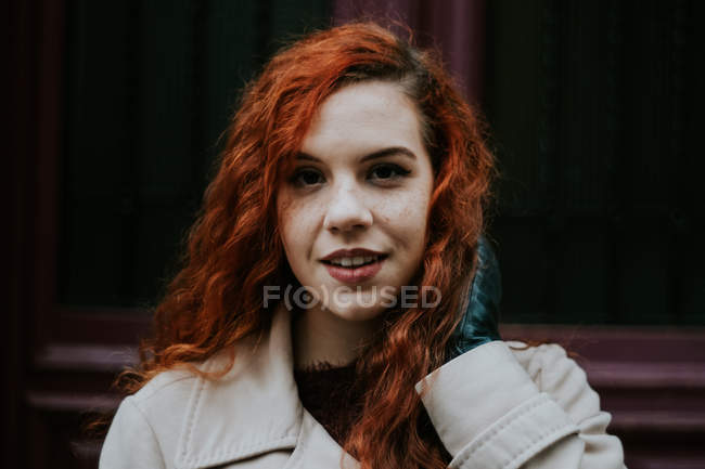 Рыжая женщина касается волос и смотрит в камеру — стоковое фото