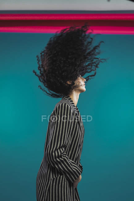 Vue latérale de la femme bouclée secouant les cheveux — Photo de stock
