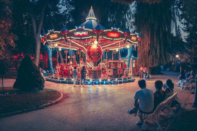 Merry-go-round illuminated carousel in green park at night. — Stock Photo