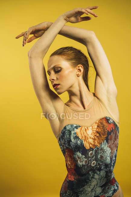 Молодая рыжая женщина танцует с поднятыми в студии руками — стоковое фото