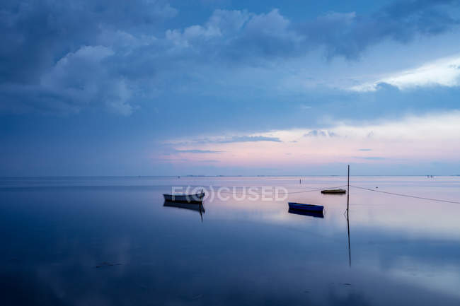 Boats moored at calm sea surface at dusk — Stock Photo