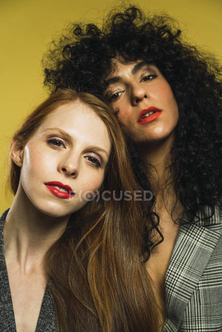 Портрет двух женщин, обнимающих друг друга и смотрящих в камеру в студии — стоковое фото
