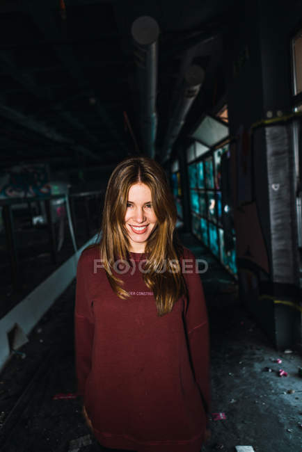 Femme souriante debout et posant dans un bâtiment altéré . — Photo de stock