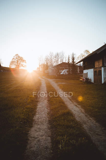 Vista al camino rural en el campo en casas de madera a la luz del sol - foto de stock