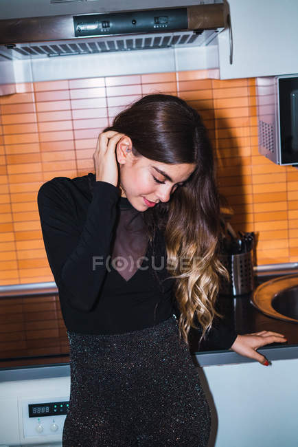 Alegre bonita mujer de pie en la cocina y establecer el pelo - foto de stock
