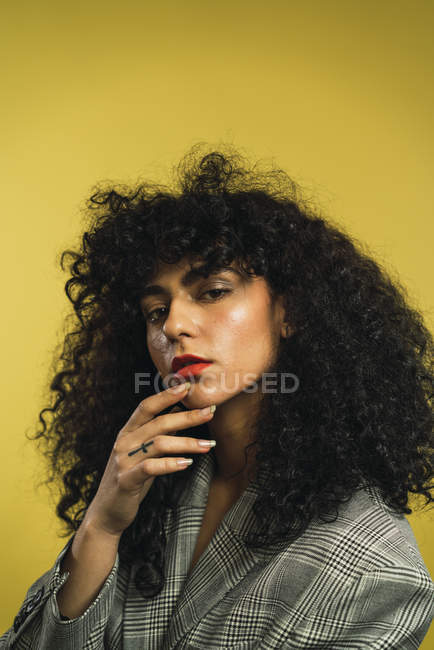Curly mulher tocando queixo e olhando para a câmera — Fotografia de Stock