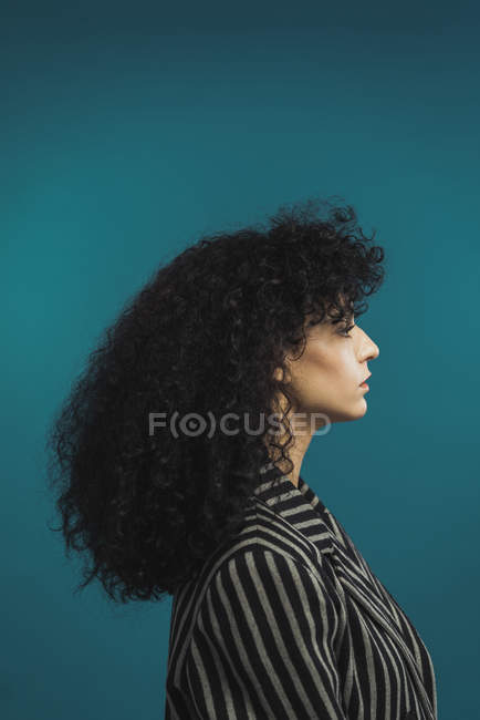 Side view of curly woman posing on blue background — Stock Photo
