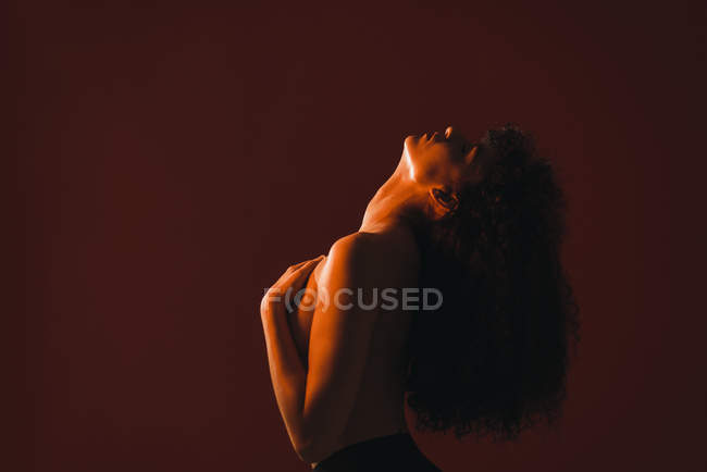 Femme bouclée seins nus posant sur fond rouge — Photo de stock