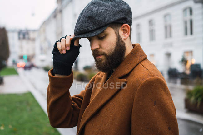Homem elegante em aveia vintage tocando boné e olhando para baixo — Fotografia de Stock